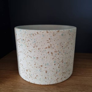 Può includere: Un vaso in ceramica bianca con un design a terrazzo macchiato in tonalità di marrone, beige e blu.
