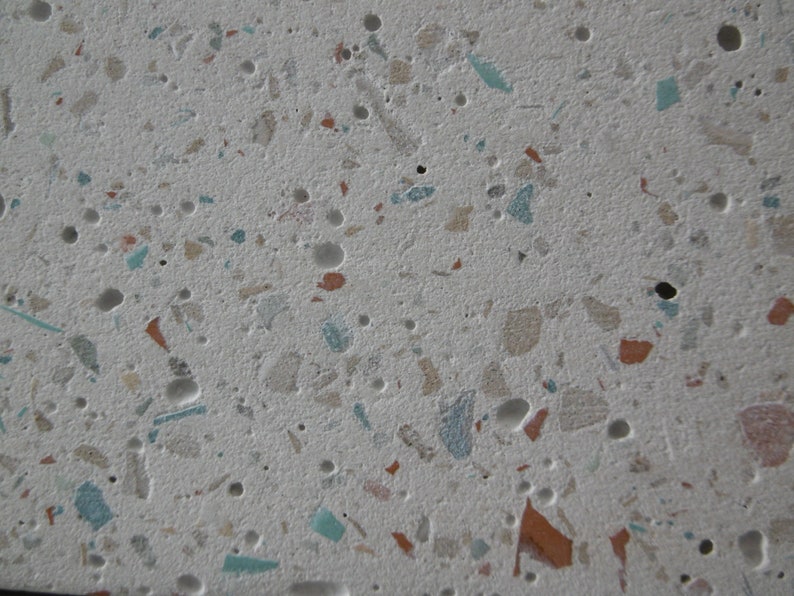 May include: A close-up of a white surface with small, colourful flecks of terrazzo. The flecks are mostly beige, brown, and blue.