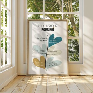 Affiche dans un grand cadre posé au sol, contre une fenêtre. Les rayons du soleil traversent la vitre, baignant l’illustration d’une lumière douce et chaleureuse qui en souligne les couleurs et le message motivant.