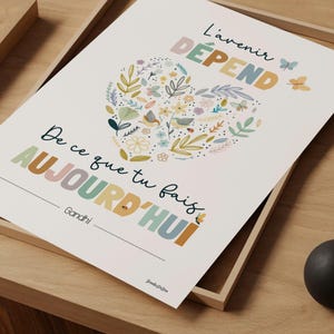 Peut inclure: Une affiche rectangulaire blanche avec une illustration en forme de cœur composée de fleurs, de feuilles et de papillons colorés. Le texte indique : L'avenir DÉPEND De ce que tu fais AUJOURD'HUI, suivi du nom Gandhi et d'un petit logo en bas.