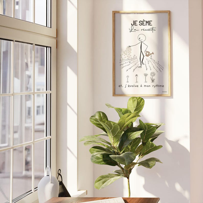 Un bonhomme bâton minimaliste et esthétique sème des graines dans un jardin. Il disperse soigneusement des graines. Des fleurs épanouies et d’autres en train d’éclore illustrent le titre ‘Je sème la réussite’. L'affiche est présentée dans un cadre accroché sur un mur blanc à côté d'une fenêtre ouverte. La pièce est ensoleillée et il y a un bureau et une grande plante verte.