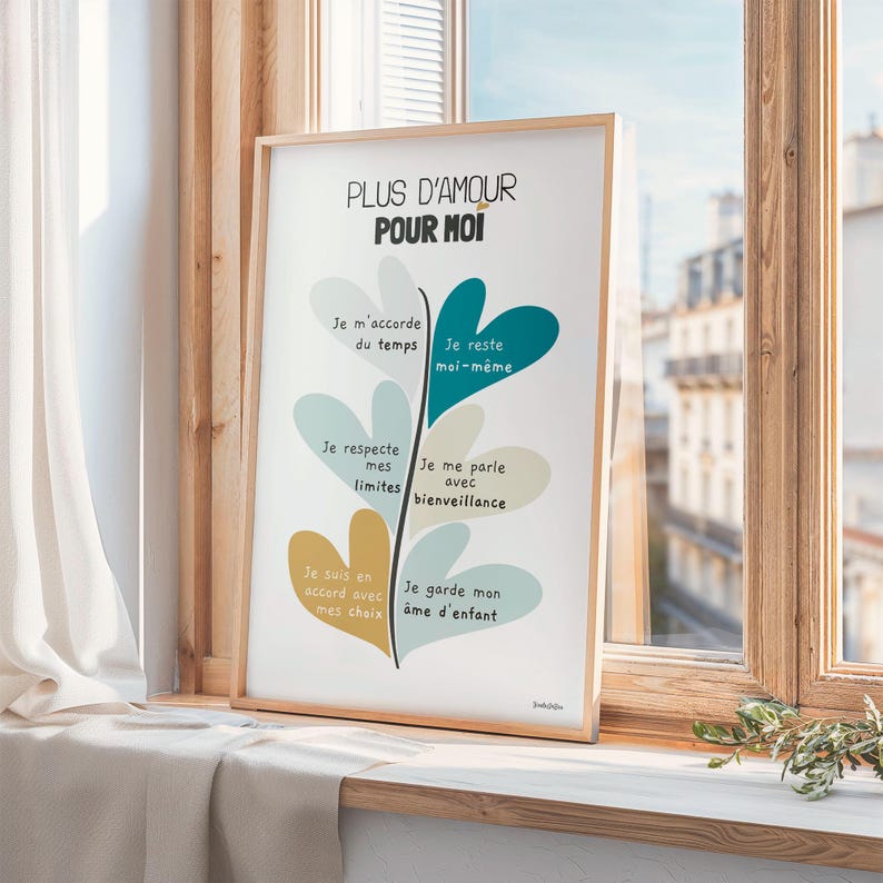 Affiche dans un cadre en bois, vue de biais sur un rebord de fenêtre. Derrière, de jolis immeubles. Une branche d’olivier repose à côté, encadrée par des rideaux gris. L’ambiance est douce et urbaine.