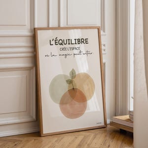 Può includere: Una stampa artistica incorniciata con il testo francese "L'ÉQUILIBRE" e "CRÉE L'ESPACE où la magie peut entrer". L'opera presenta tre cerchi sovrapposti in colori tenui e una piccola illustrazione di una pianta. La cornice è in legno chiaro.