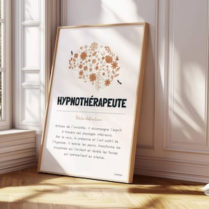 May include: A framed print with the word "HYPNOTHÉRAPEUTE" in dark blue, featuring a floral brain illustration in shades of brown and beige. The print includes descriptive text in French, leaning against a white wall and wooden floor.