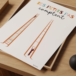 Op de afbeelding: Een witte rechthoekige print met de tekst "TES PETITS PAS comptent" in veelkleurige letters. Het ontwerp bevat twee hoge oranje ladders, één met een klein figuurtje dat bovenaan klimt en één met een figuurtje dat aan een sport hangt.