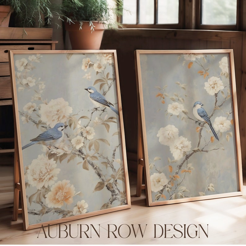 Puede incluir: Dos impresiones enmarcadas con un dise&ntilde;o floral azul y blanco y p&aacute;jaros azules. Las impresiones est&aacute;n en marcos de madera y est&aacute;n apoyadas contra una pared de madera.