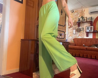 May include: A pair of lime green wide-leg pants with a high waist. The pants are made of a smooth, silky fabric and have a relaxed fit. The model is wearing the pants with a white platform heel.