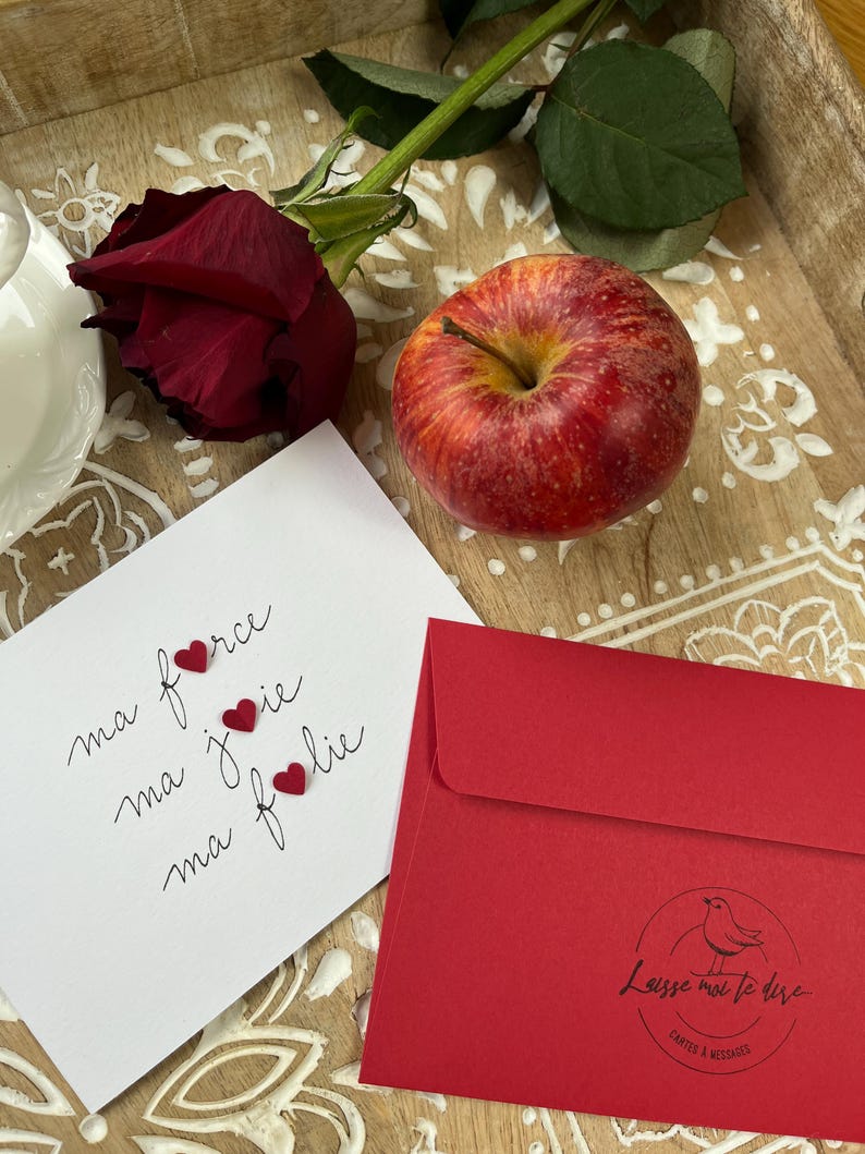 Carte d'amour ou d'amitié.
Carte blanche, double sur laquelle est écrit à la plume, sur 3 lignes :
Ma force
Ma joie
Ma folie
3 cœurs rouges légèrement pliés et collés par leur centre, forment les O de force, joie et folie.
Enveloppe assortie fournie.