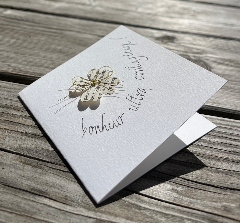 Carte pour souhaiter du bonheur.
Carte double blanche 9x9 cm et son enveloppe. un trèfle à 4 feuilles est fixé par un fil doré, sous lequel est écris: bonheur ultra contagieux ! la phrase suit le contour du trèfle et s'envole.