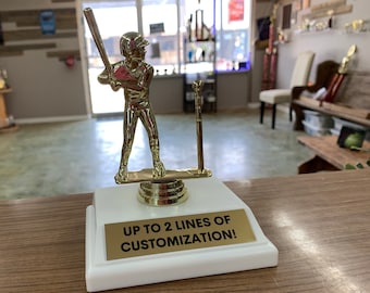 May include: Gold-colored baseball player trophy with a white base. The base has a gold plate with the text "UP TO 2 LINES OF CUSTOMIZATION!"