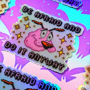 Puede incluir: Pegatinas hologr&aacute;ficas con la frase "BE AFRAID AND DO IT ANYWAY" y una imagen pixelada de Coraje, el perro cobarde. Las pegatinas tienen un borde festoneado y est&aacute;n dispersas sobre un fondo morado y azul estampado.