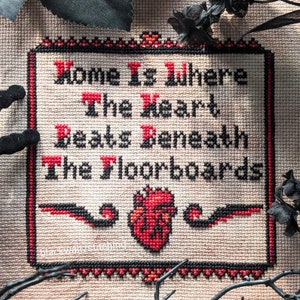 Peut inclure: Broderie au point de croix avec un cœur rouge et le texte "Home is where the heart beats beneath the floorboards".