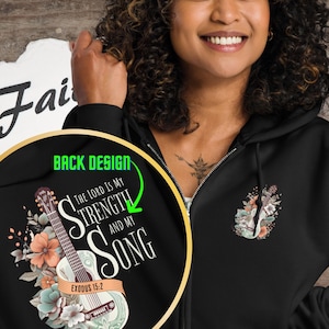 May include: Black zip-up hoodie with a guitar and floral design on the back. The design includes the text "THE LORD IS MY STRENGTH AND MY SONG" and "EXODUS 15:2". A smaller guitar and floral design is on the front.
