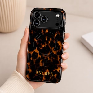 Może przedstawiać: Czarno-brązowe etui na telefon z wzorem skorupy żółwia. Etui posiada czarny moduł aparatu z trzema obiektywami i imię "ANDREA" złotymi literami. Zaprojektowane dla smartfona.