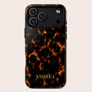 Puede incluir: Funda de teléfono negra y marrón con un diseño de carey. La funda tiene un módulo de cámara negro con tres lentes y el nombre "ANDREA" en letras doradas. Diseñada para un smartphone.
