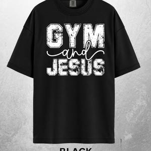 May include: Black t-shirt with the text "GYM and JESUS" in distressed white lettering. The word "and" is in a cursive font. The word "BLACK" is printed at the bottom of the shirt.
