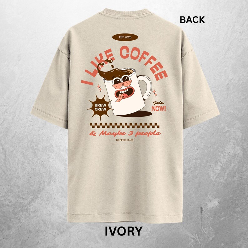 May include: Ivory-colored t-shirt with a coffee-themed graphic on the back. The design features a cartoon coffee mug with the text "I Like Coffee" and "Brew Crew." Additional text includes "& Maybe 3 people" and "Join Now!"