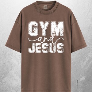 May include: Espresso-colored t-shirt with the text "GYM and JESUS" in distressed white lettering. The shirt has a crew neck and short sleeves. The word "ESPRESSO" is printed at the bottom of the shirt.
