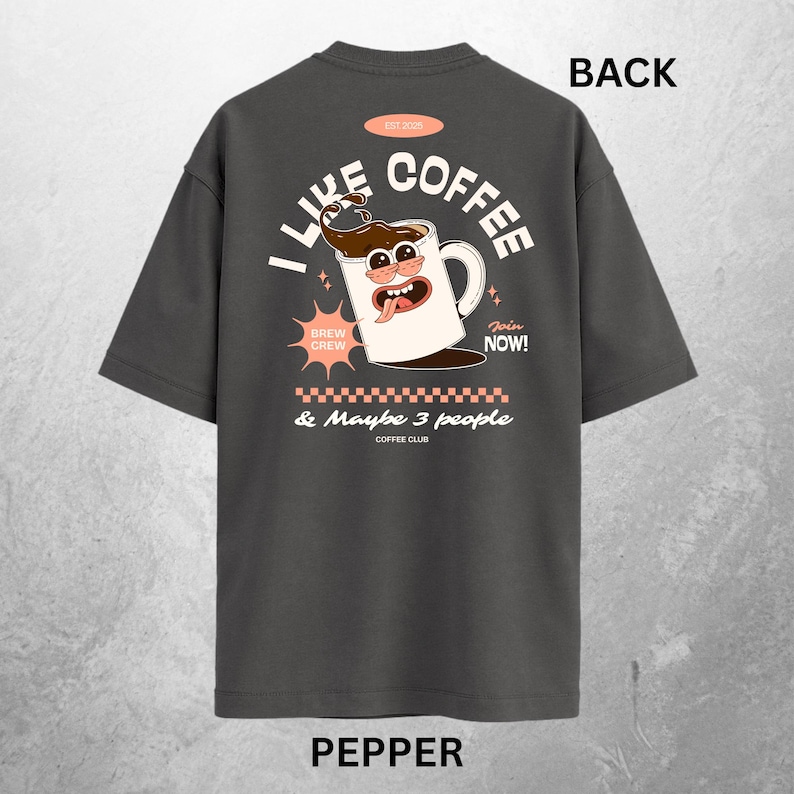 May include: Pepper-colored t-shirt with a coffee-themed graphic. The design features a cartoon coffee mug with a face, the words "I Like Coffee" and "& Maybe 3 people Coffee Club". The shirt also has the words "Join Now!" and "Brew Crew".