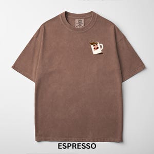 May include: Brown t-shirt with a crew neck and short sleeves. The shirt features a cartoon coffee cup graphic on the front and the word "ESPRESSO" at the bottom. The shirt has a vintage, washed look.