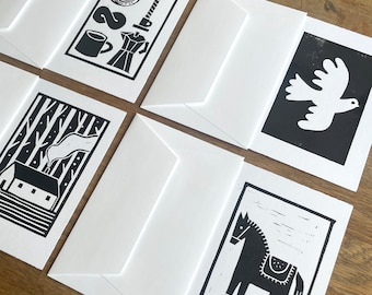 May include: Six black and white greeting cards with different designs. The designs include a coffee pot, a mug, a spiral, a candle, a bird, a house, a forest, and a horse.