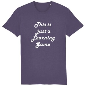 Peut inclure: T-shirt violet avec un texte blanc qui dit "This is just a learning game".