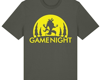 May include: A khaki t-shirt with a yellow graphic of a werewolf howling at the moon. The graphic also includes trees and the text "GAMENIGHT".
