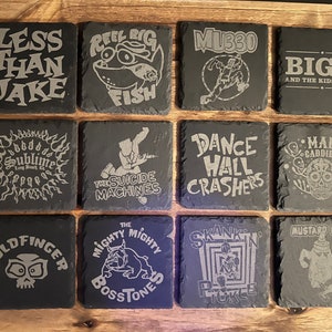 May include: A set of 12 black slate coasters with various band logos and designs, including "Less Than Jake", "Reel Big Fish", "MU330", "Big D and the Kids Table", "Sublime", "The Suicide Machines", "Dance Hall Crashers", "Mad Caddies", "Goldfinger", "The Mighty Mighty Bosstones", "Skankin' Pickle", and "Mustard Plug".