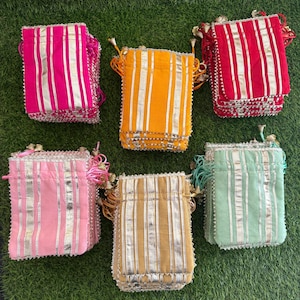 May include: A collection of six small, colorful drawstring pouches. Each pouch is a different color, including pink, yellow, red, light pink, tan, and mint green. Vertical silver stripes and decorative trim adorn each pouch, with matching drawstring cords.