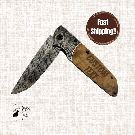 An abstract-patterned blade on a shadow wood handle — this is a custom engraved pocket knife that looks like wearable art, not a hardware-store impulse buy.