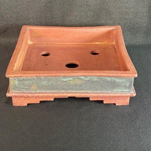 Pot à bonsaï / carré / Terre rouge avec une bande émaillée de vert bronze sur les côtés .    Bonsai pot / square / Red earth with a bronze g