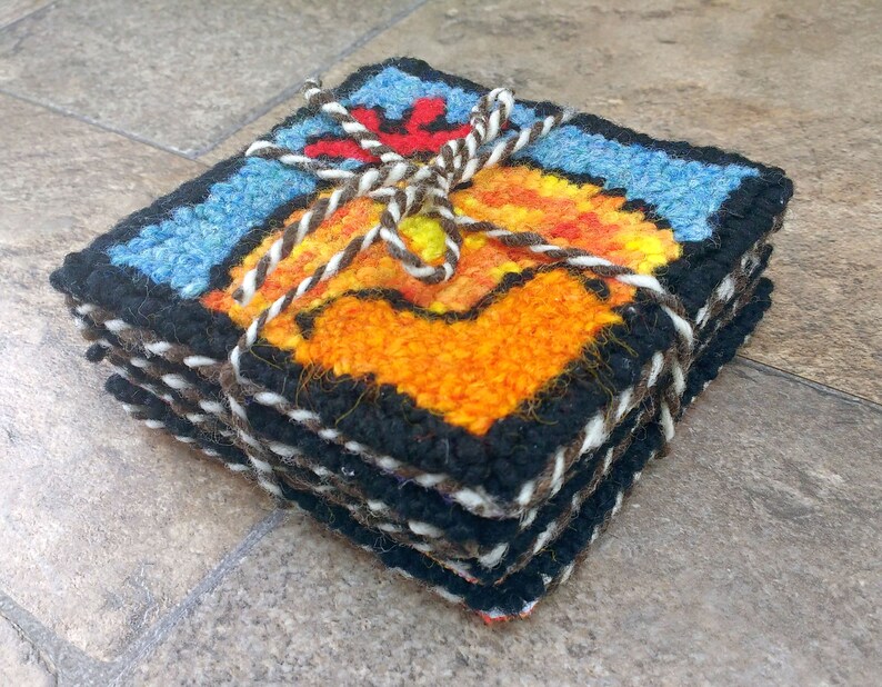 May include: A set of six colorful woven coasters featuring a rooster design. The coasters are tied together with twine and have a black border.