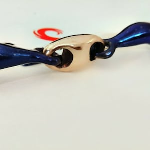 Op de afbeelding: Een blauw en gouden paardenbit met een losse ring aan de ene kant en een vaste ring aan de andere.