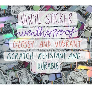May include: A collection of colorful vinyl stickers featuring a camera design with a mountain and forest scene. The stickers are weatherproof, glossy, vibrant, scratch resistant, and durable. The text "VINYL STICKER weatherproof GLOSSY AND VIBRANT SCRATCH RESISTANT AND DURABLE" is written on the stickers.