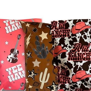 May include: Three different patterned mailing bags. The first bag is pink with white stars and the text "Yee Haw" repeated. The second bag is brown with white stars and a cactus design. The third bag is white with black cow spots and the text "A Lil' Ranch" repeated.