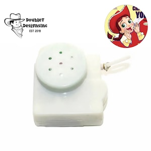 May include: A white plastic sound module with a circular speaker and a pull string. The speaker has several small holes. A cartoon image of a cowgirl is in the background. The logo for Double T Designs Inc. is also visible.