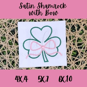 May include: Green satin shamrock with a pink satin bow. The shamrock is outlined in green and the bow is outlined in pink. The image includes the text "Satin Shamrock with Bow" and the sizes "4x4", "5x7", and "6x10".