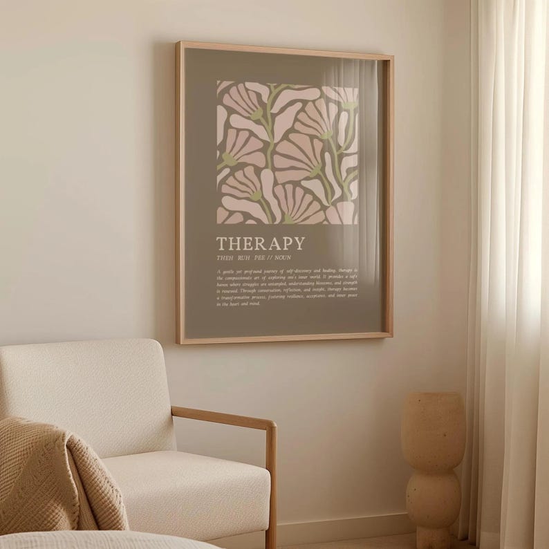 May include: A framed art print featuring a floral design in pink and green hues on a muted background. The word "THERAPY" is displayed in a bold font, with additional text below. The artwork is displayed in a light-colored wooden frame.