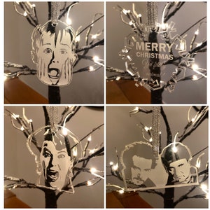 Puede incluir: Cuatro adornos navideños de acrílico transparente con personajes de la película Solo en casa. Los adornos cuelgan de una cinta plateada. El primer adorno presenta un primer plano de la cara de Kevin McCallister. El segundo adorno presenta un diseño de copo de nieve con el texto "Feliz Navidad, sucio animal!" El tercer adorno presenta un primer plano de la cara de Marv Merchants. El cuarto adorno presenta un primer plano de la cara de Harry Lime.