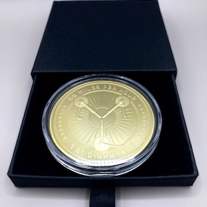 May include: A gold-colored coin with a clear plastic case. The coin features a stylized image of the DeLorean time machine from the movie Back to the Future. The text "88 Miles Per Hour" and "1.21 Gigawatts" are inscribed around the edge of the coin.