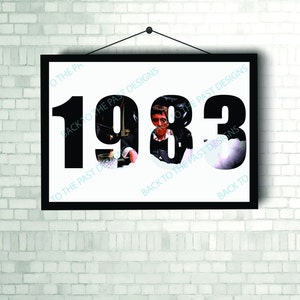 May include: A black and white framed print with the year 1983 in large black numbers. The numbers are partially obscured by a black and white photo of a man.