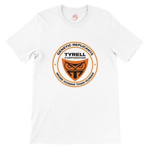May include: White t-shirt with a circular orange and black graphic. The graphic reads "GENETIC REPLICANTS TYRELL CORPORATION MORE HUMAN THAN HUMAN" and features an owl-like design.