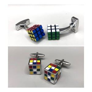 Op de afbeelding: Een paar zilveren manchetknopen met een kleurrijk Rubik's Cube-ontwerp. De kubussen zijn rood, geel, blauw, groen en wit.