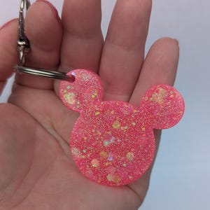 Op de afbeelding: Roze glitter muis oren sleutelhanger met een zilveren sleutelring.