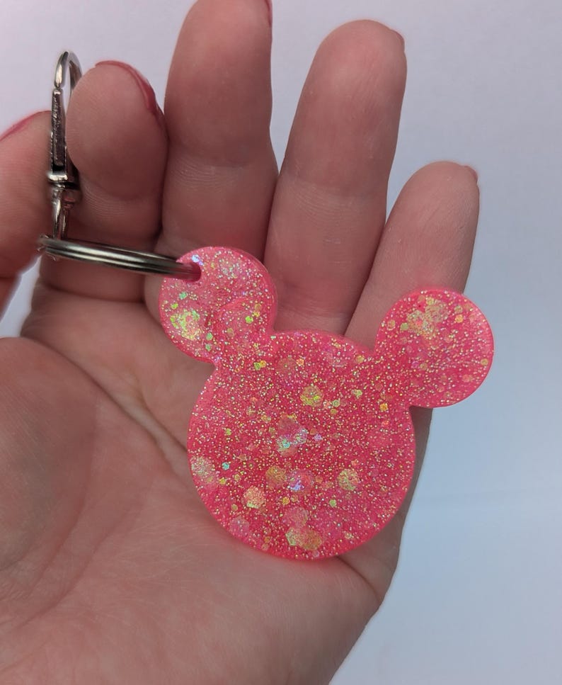 Op de afbeelding: Roze glitter muis oren sleutelhanger met een zilveren sleutelring.
