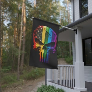 May include: A black flag featuring a rainbow-coloured skull and crossbones design. The skull is styled to resemble the Punisher logo. The rainbow colours are red, orange, yellow, green, blue, indigo, and violet. The skull has a white star pattern on the forehead.