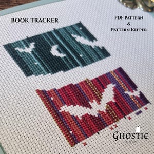 May include: Cross-stitch pattern featuring two book-shaped designs with bat and moon motifs. The top design is teal and the bottom is red and purple. Text includes "BOOK TRACKER" and "PDF PATTERN & PATTERN KEEPER". The Ghostie Stitches logo is in the bottom right.