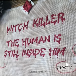 May include: Cross-stitch embroidery with the text "WITCH KILLER THE HUMAN IS STILL INSIDE HIM" in red, dripping letters. The beige fabric has a spool of red thread and the "Ghostie stitches" logo.