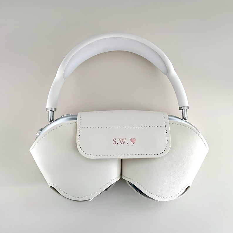 May include: White leather headphone case with a silver zip and a pink heart with the initials "S.W." on the front.