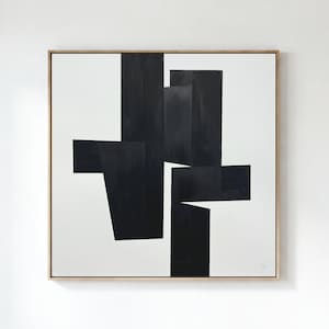 Pode incluir: Obra de arte geométrica abstrata em preto e branco em uma moldura de madeira. A obra apresenta formas angulares arrojadas em preto sobre um fundo branco. A arte emoldurada é quadrada e está pendurada em uma parede branca.